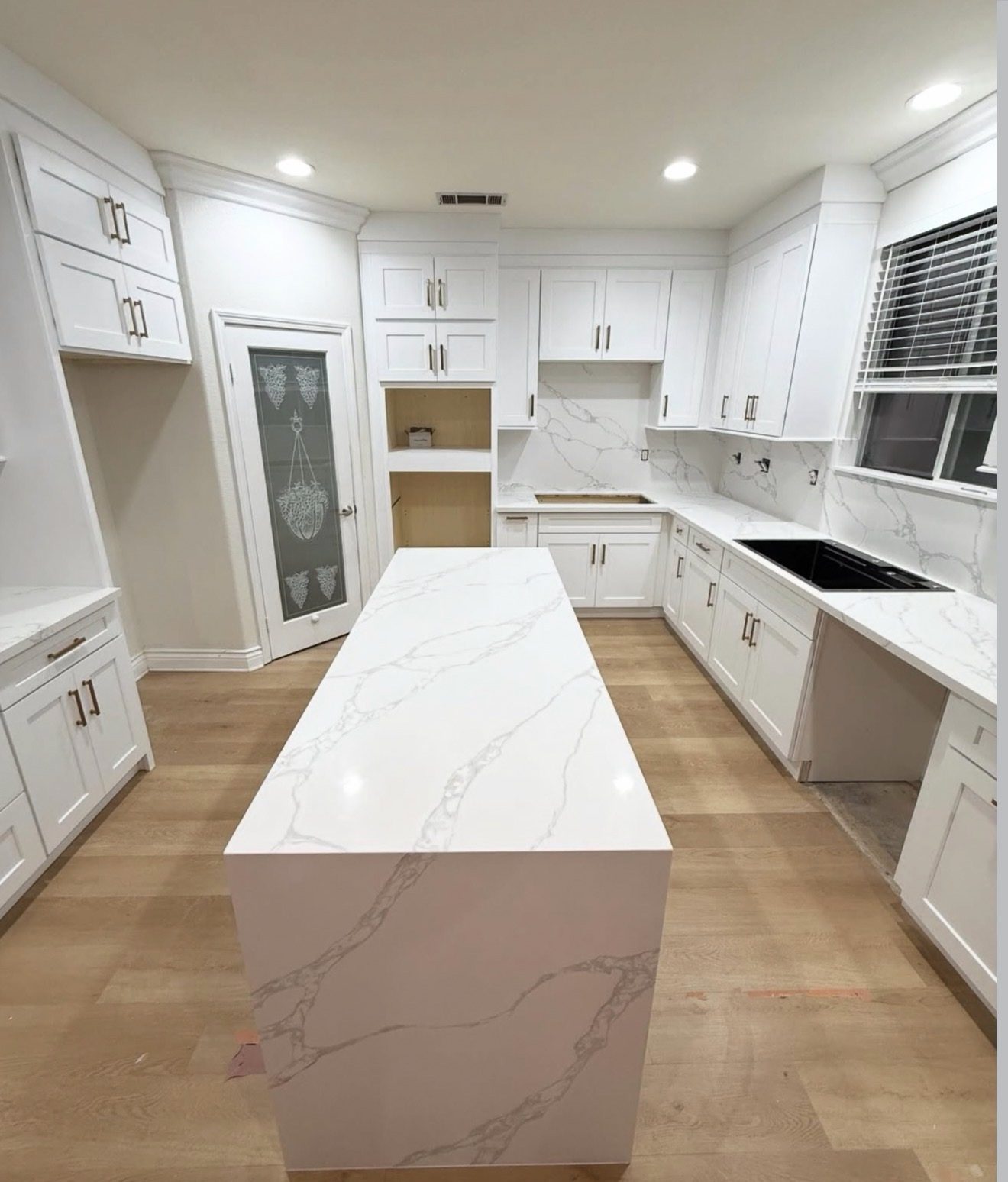 Custom white shaker kitchen with marble waterfall island by Perini Cabinets